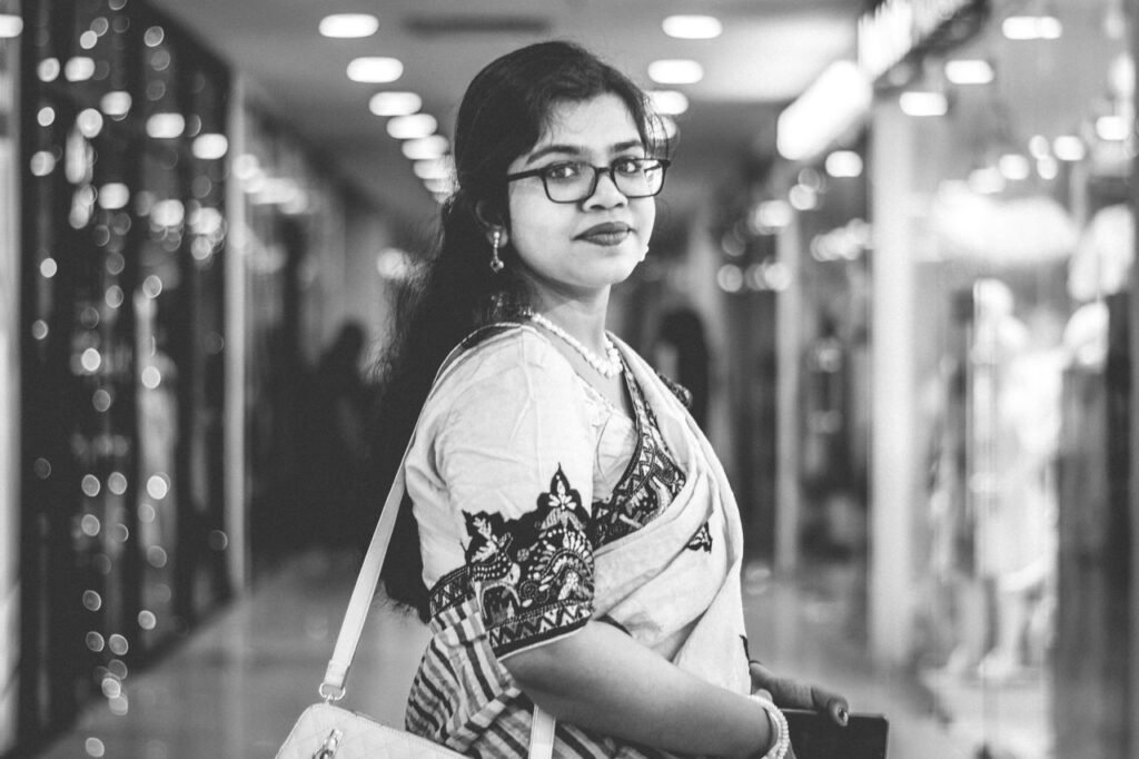 About Black and white portrait of a woman in traditional attire shopping in a modern mall.