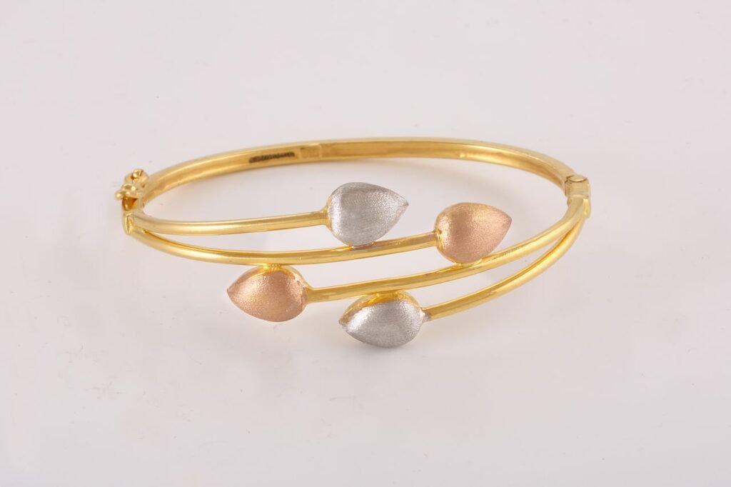Home Stylish gold bangle featuring a unique leaf design in silver and rose gold accents.