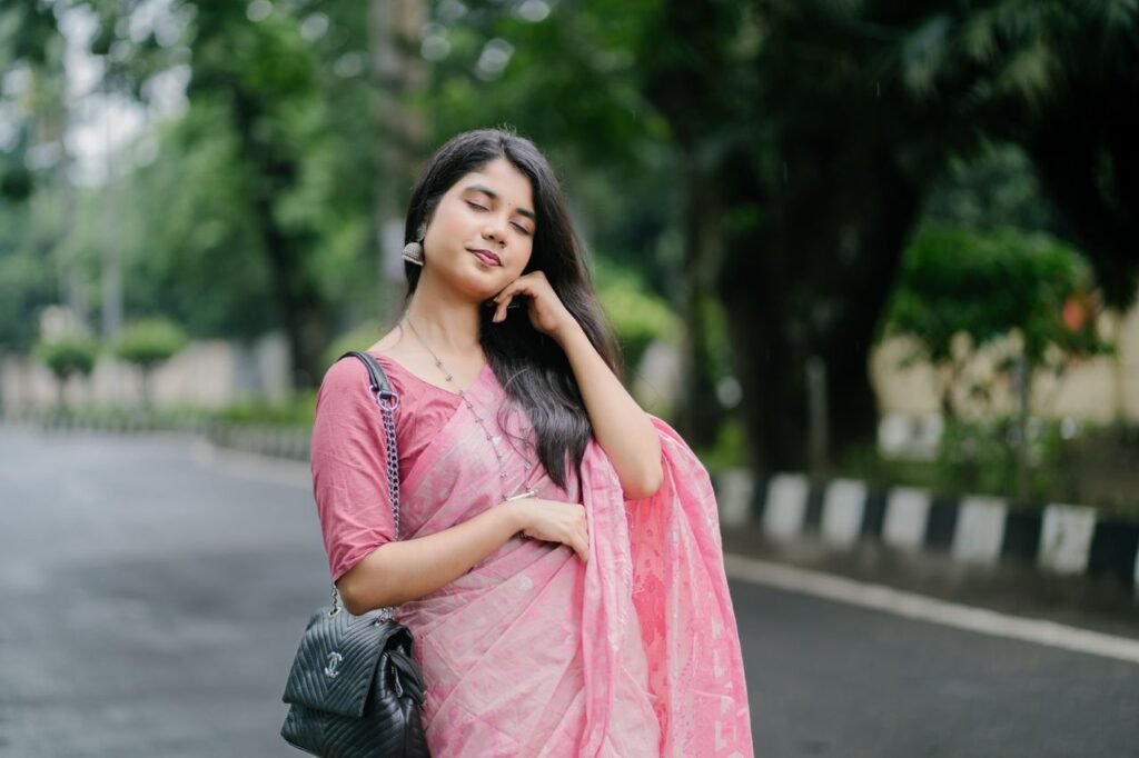 Menu Beautiful young woman in pink saree, standing on a serene urban street. Calm and elegant pose.
