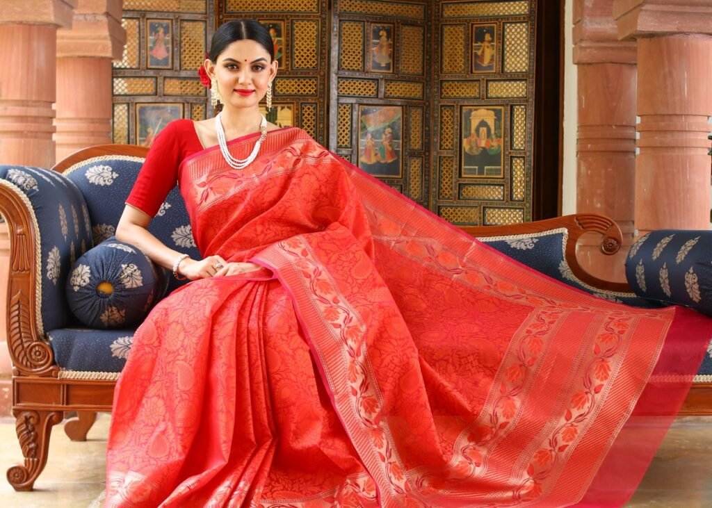 Home Woman in red saree poses elegantly indoors, highlighting traditional fashion and culture.