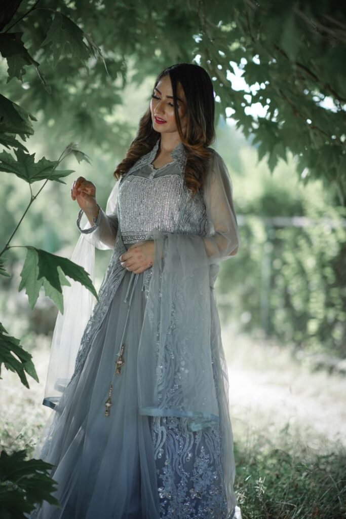 Home A graceful woman in a beautiful traditional gown amidst lush greenery, embodying elegance.
